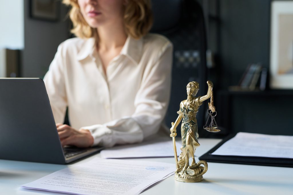 Attorney working at a laptop beside a Lady Justice figurine